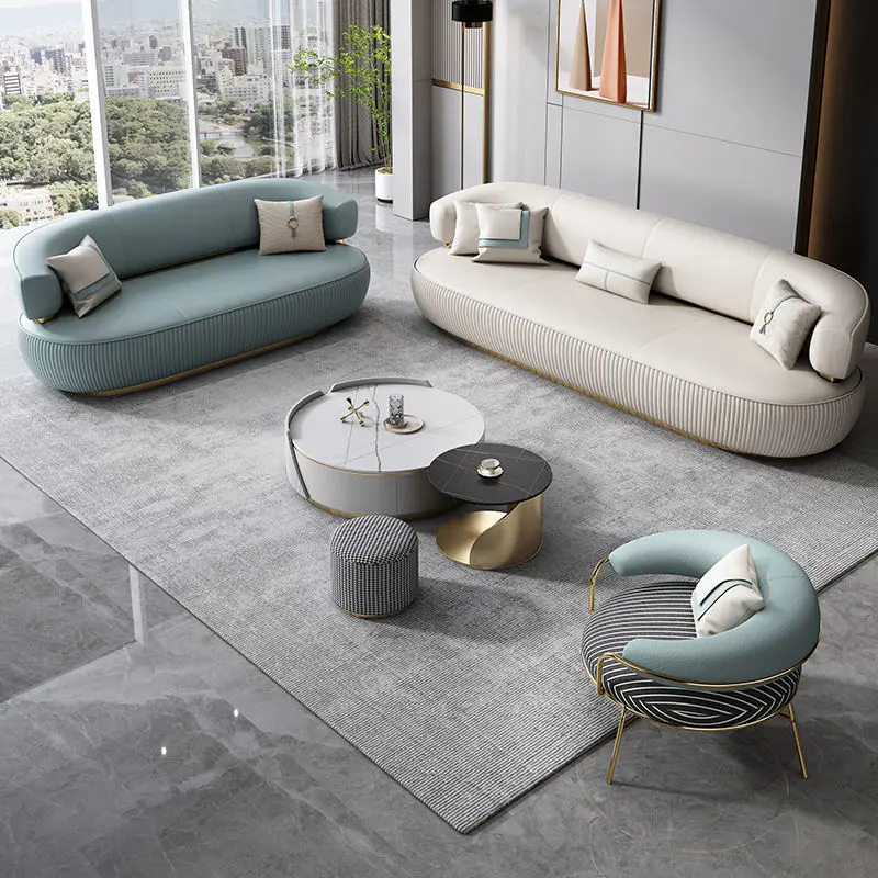 Ensemble de salon de luxe au design contemporain, comprenant deux canapés incurvés et un fauteuil assorti avec une base cannelée et des pieds en métal doré. Ameublement Hicham Marrakech.