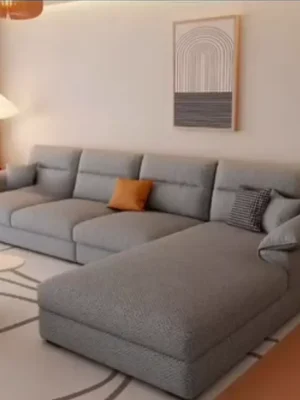 Canapé d'angle moderne avec méridienne en tissu gris texturé, parfait pour un salon contemporain. Vendu par Ameublement Hicham à Marrakech.