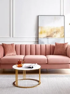 Superbe canapé 3 places de style Art Déco en velours rose, avec un capitonnage vertical et d'élégants pieds en métal doré. Ameublement Hicham Marrakech.