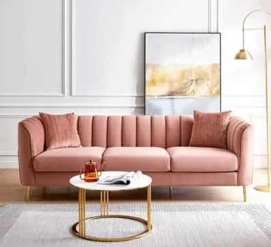 Superbe canapé 3 places de style Art Déco en velours rose, avec un capitonnage vertical et d'élégants pieds en métal doré. Ameublement Hicham Marrakech.