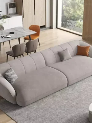 Canapé moderne au design unique avec capitonnage vertical et formes arrondies, en tissu doux gris clair, vendu par Ameublement Hicham à Marrakech.