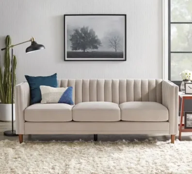 Canapé de style scandinave 3 places en tissu beige, avec un dossier à capitonnage vertical et des pieds en bois. Ameublement Hicham Marrakech.