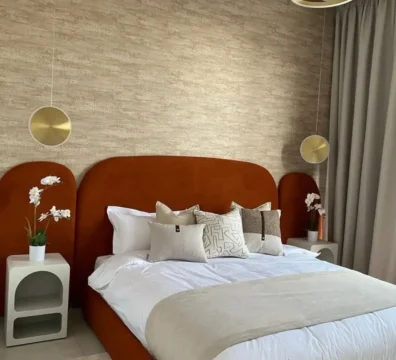 Superbe lit moderne avec une haute tête de lit arrondie en velours terracotta (orange brûlé), pour une chambre design. Ameublement Hicham Marrakech.
