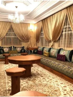 Luxueux salon marocain traditionnel avec sedari en tissu riche vert et doré, tables en bois sculpté et coussins assortis, disponible chez Ameublement Hicham à Marrakech.