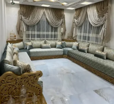 Magnifique salon marocain traditionnel avec structure en bois doré sculpté et tissu artisanal bleu-vert, disponible chez Ameublement Hicham à Marrakech.