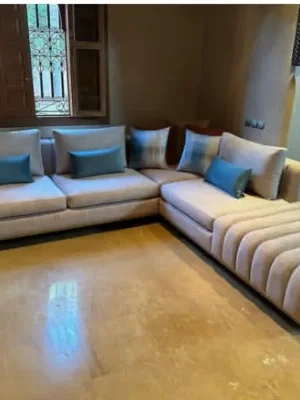 Canapé d'angle de style design avec une méridienne au capitonnage original, en tissu beige texturé. Vente chez Ameublement Hicham à Marrakech.