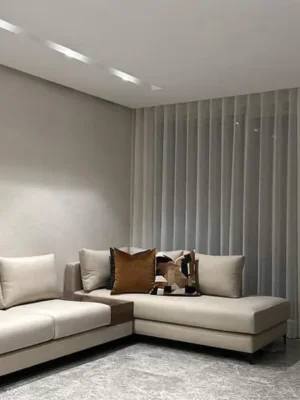 Canapé d'angle de style minimaliste avec une large méridienne, en tissu blanc cassé, pour un salon moderne et épuré. Ameublement Hicham Marrakech.