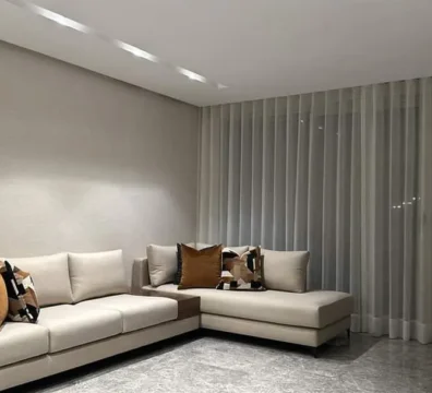 Canapé d'angle de style minimaliste avec une large méridienne, en tissu blanc cassé, pour un salon moderne et épuré. Ameublement Hicham Marrakech.