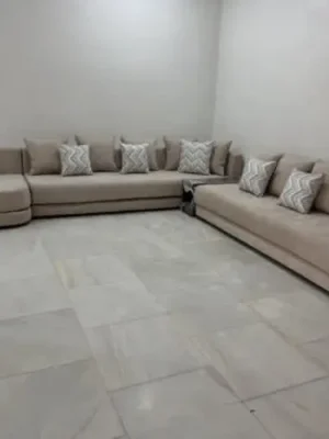 Canapé panoramique moderne en U en tissu beige, agrémenté de coussins à motifs géométriques, conçu pour un grand salon familial. Ameublement Hicham Marrakech.