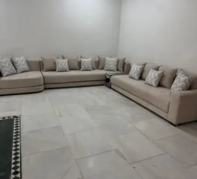 Canapé panoramique moderne en U en tissu beige, agrémenté de coussins à motifs géométriques, conçu pour un grand salon familial. Ameublement Hicham Marrakech.