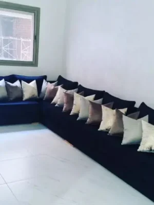 Grand canapé d'angle panoramique en velours bleu nuit, accompagné de nombreux coussins décoratifs dans une pièce lumineuse. Ameublement Hicham Marrakech.