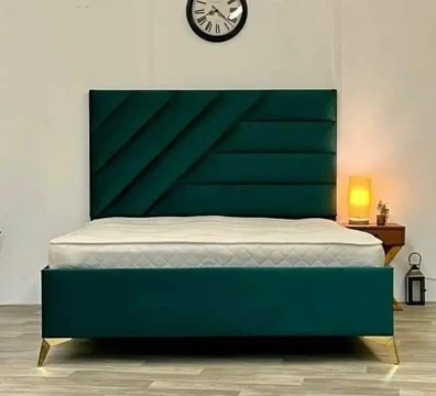 Lit design moderne avec une tête de lit géométrique à motifs diagonaux en velours vert foncé et de fins pieds dorés. Ameublement Hicham.