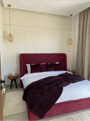 Lit double au design moderne avec cadre et tête de lit entièrement tapissés en velours ou tissu texturé bordeaux. Ameublement Hicham Marrakech.