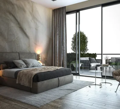 Lit moderne et simple avec une tête de lit capitonnée en tissu taupe, dans une chambre avec un mur en béton ciré. Ameublement Hicham Marrakech.