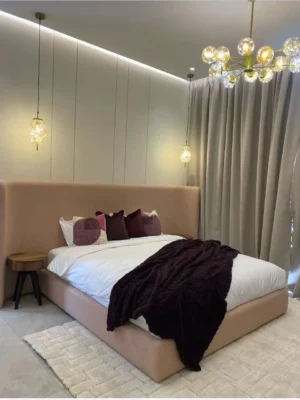 Lit double au design chic et moderne, avec une haute tête de lit à oreilles en tissu texturé rose poudré. Ameublement Hicham Marrakech.