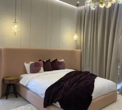 Lit double au design chic et moderne, avec une haute tête de lit à oreilles en tissu texturé rose poudré. Ameublement Hicham Marrakech.