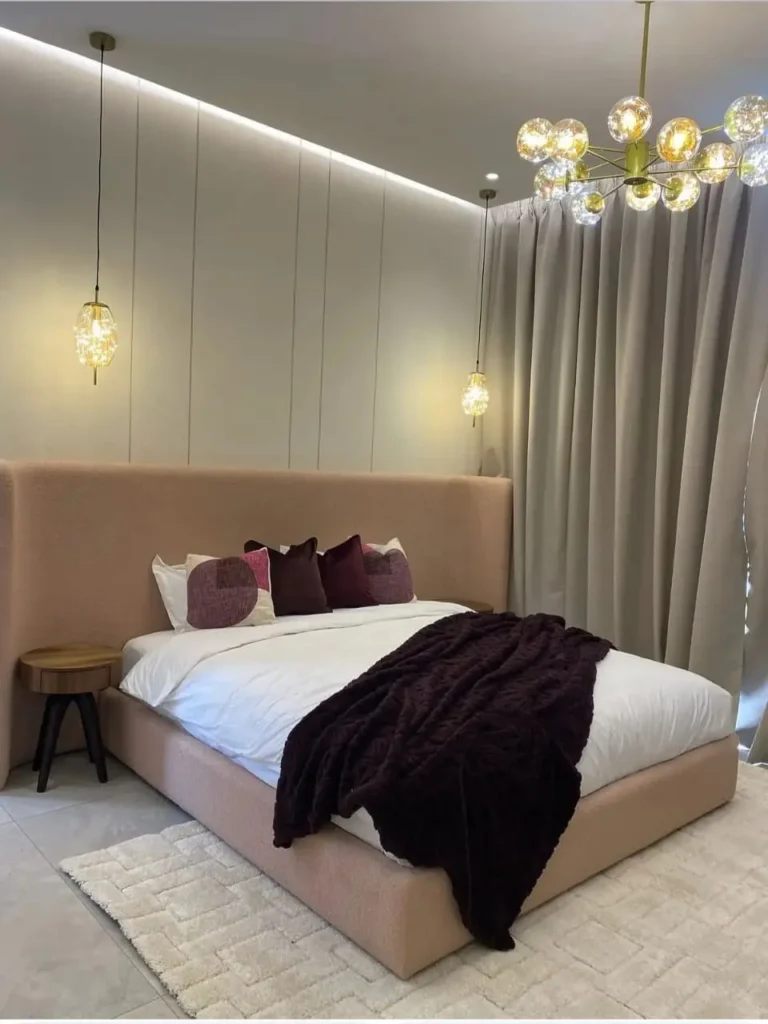 Lit double au design chic et moderne, avec une haute tête de lit à oreilles en tissu texturé rose poudré. Ameublement Hicham Marrakech.