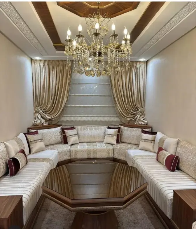 Luxueux salon marocain en U avec sedari en tissu blanc et bordeaux, et une table en verre octogonale, dans un décor élégant. Ameublement Hicham Marrakech.