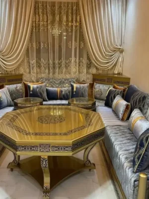 Salon marocain traditionnel avec sedari en tissu bleu et gris, agrémenté d'une table octogonale dorée et de riches coussins. Ameublement Hicham Marrakech.