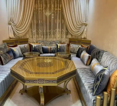 Salon marocain traditionnel avec sedari en tissu bleu et gris, agrémenté d'une table octogonale dorée et de riches coussins. Ameublement Hicham Marrakech.