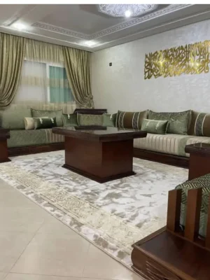 Salon marocain traditionnel avec sedari en tissu vert sauge et structure en bois foncé, complété par une table basse carrée. Ameublement Hicham Marrakech.