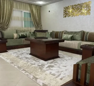 Salon marocain traditionnel avec sedari en tissu vert sauge et structure en bois foncé, complété par une table basse carrée. Ameublement Hicham Marrakech.