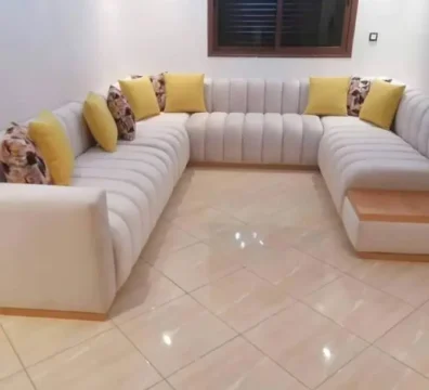 Grand salon moderne panoramique en U avec un capitonnage tubulaire, en tissu blanc cassé, rehaussé de coussins jaunes vifs. Ameublement Hicham Marrakech.