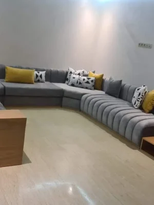 Grand salon moderne panoramique en U, en velours gris anthracite, avec un design à capitonnage tubulaire et des coussins jaunes vifs. Ameublement Hicham Marrakech.