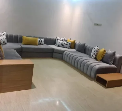 Grand salon moderne panoramique en U, en velours gris anthracite, avec un design à capitonnage tubulaire et des coussins jaunes vifs. Ameublement Hicham Marrakech.
